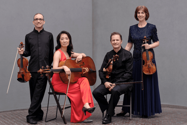 The artists pose with their instruments, smiling at the camera.